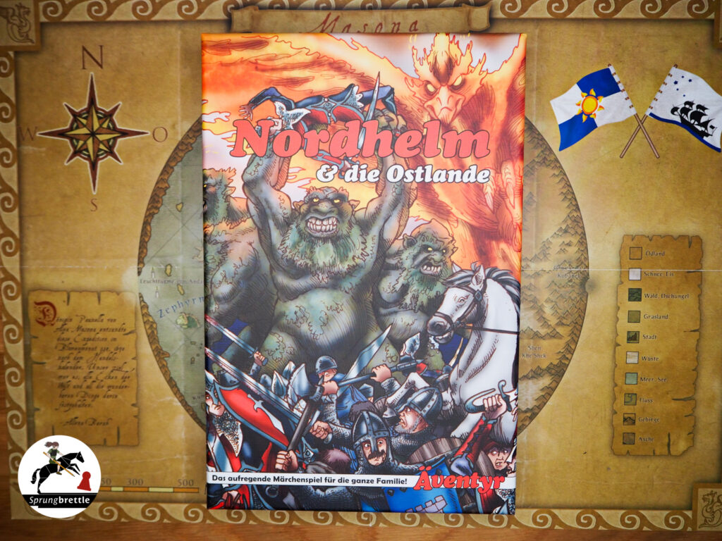 Die Spielschachtel von "Nordhelm & die Ostlande" liegt mittig auf der bräunlichen Landkarte. Im unteren Dritteln tümmelt sich auf sehr engem Raum eine Vielzahl von Rittern mit grauer Rüstung. Die Schwerter erhoben kämpfen sie gegen die im Hintergrund stehenden, deutlich größeren, grünbräunlichen, felligen Kreaturen mit großen Zähnen und gelben Augen. Im oberen Drittel überragt ein Feuerdrache mit orange rot leuchtendem Körper und ausgebreiteten Schwingen, das Geschehen.