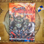 Die Spielschachtel von "Nordhelm & die Ostlande" liegt mittig auf der bräunlichen Landkarte. Im unteren Dritteln tümmelt sich auf sehr engem Raum eine Vielzahl von Rittern mit grauer Rüstung. Die Schwerter erhoben kämpfen sie gegen die im Hintergrund stehenden, deutlich größeren, grünbräunlichen, felligen Kreaturen mit großen Zähnen und gelben Augen. Im oberen Drittel überragt ein Feuerdrache mit orange rot leuchtendem Körper und ausgebreiteten Schwingen, das Geschehen.